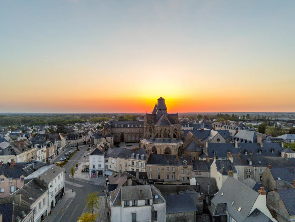 Coucher de soleil derrière la Basilique Notre-Dame-de-l’Épine - vue drone sur une partie de la ville d'Évron en Mayenne