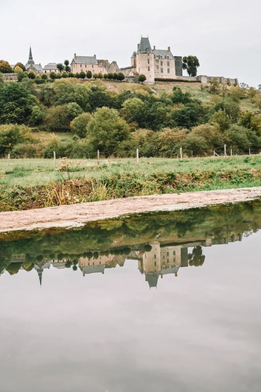 Vue sur le Château de Sainte-Suzanne en Mayenne depuis la rivière de l'Erve en contrebas de la cité médiévale, avec le reflet du château dans l'eau comme un miroir.