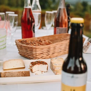 Apéro dans les Coëvrons en Mayenne avec des produits locaux - Bierres et fromages sur une nappe blanche au sommet de la colline du Montaigu à Hambes