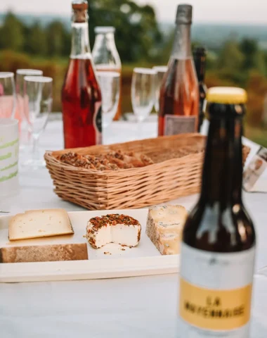 Apéro dans les Coëvrons en Mayenne avec des produits locaux - Bierres et fromages sur une nappe blanche au sommet de la colline du Montaigu à Hambes