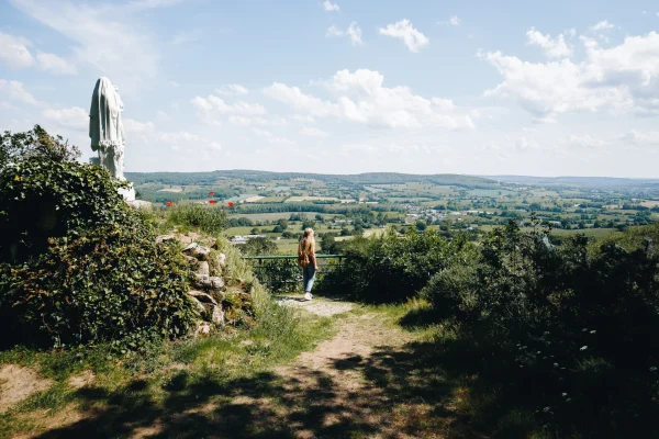 Une femme observant le paysage bocager de la Mayenne depuis de point de vue de Notre Dame des Champs en Mayenne dans les Coëvrons à Saint-Georges-sur-Erve